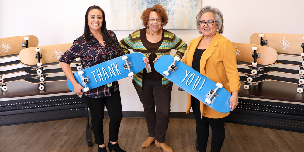 three women holding personalized skateboard