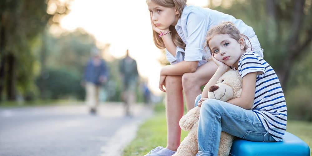 two young girls sitting by the road