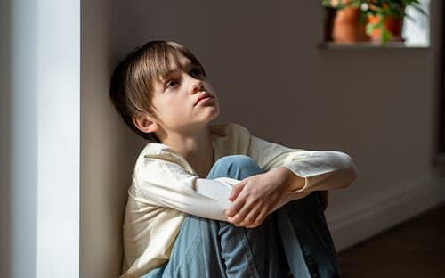 young boy sitting on the floor looking up, what is foster care like