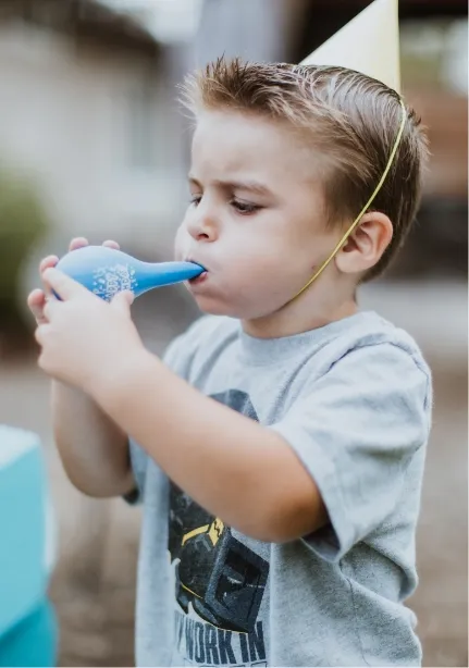 boy blowing a balloon