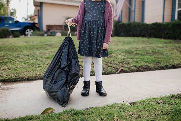 girl-holding-trashbag-on-sidewalk