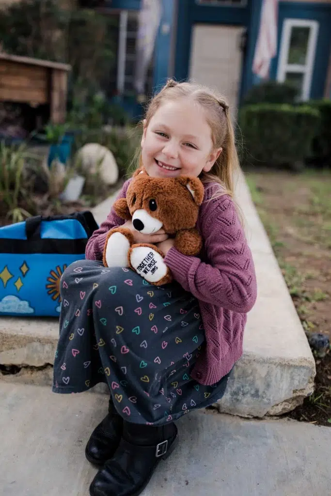 girl-hugging-bear-sitting-on-steps