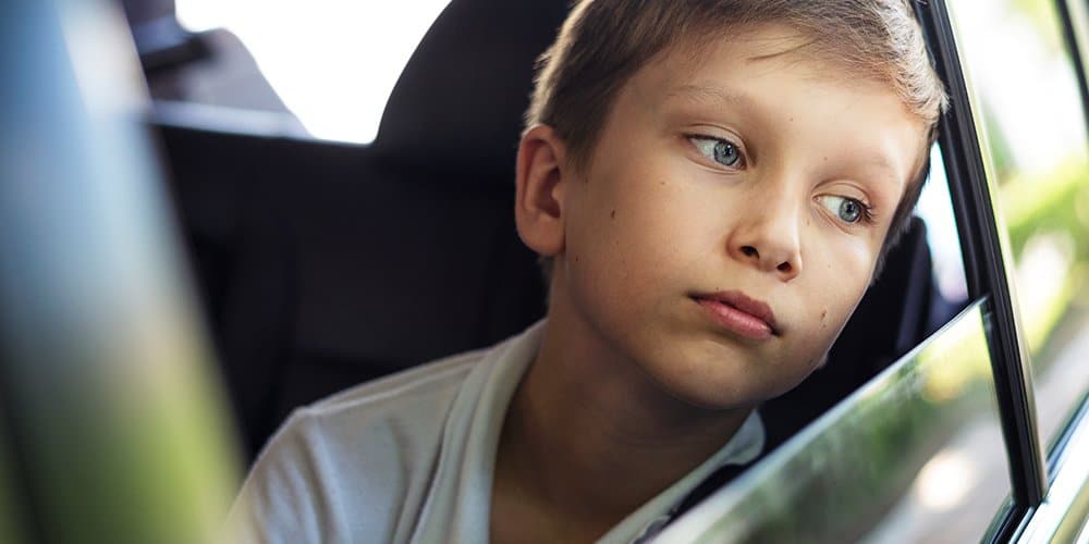 young boy sitting in the car looking out the window