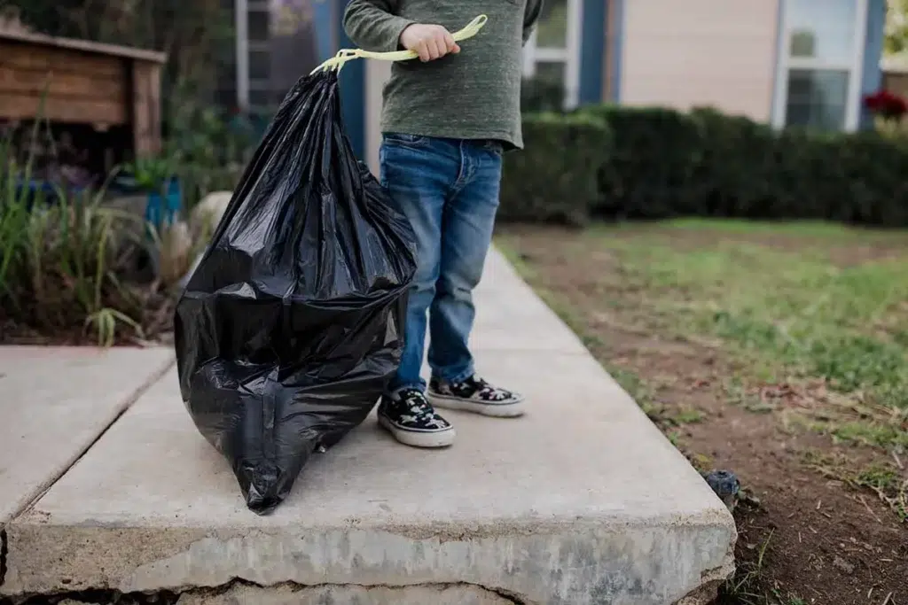 kid carrying trash bag