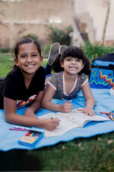 two girls laying on blanket with sweet case coloring book