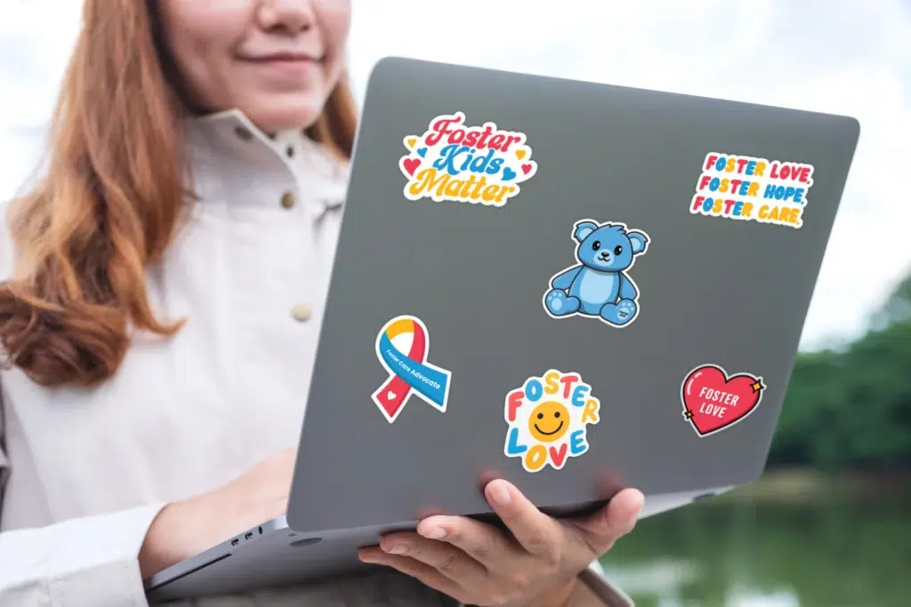 girl holding laptop covered in foster love 6 stickers