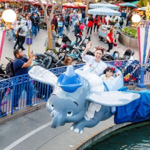 A Disney World volunteer riding Dumbo with a child