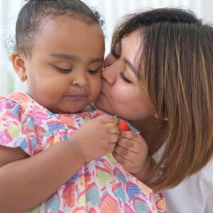 mom kissing her daughter's cheek
