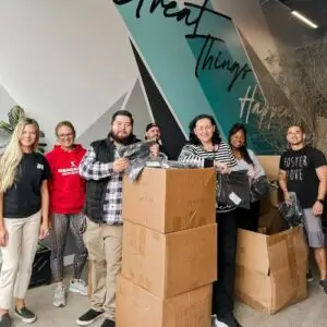 volunteers standing with donation boxes in front of a foster love mural