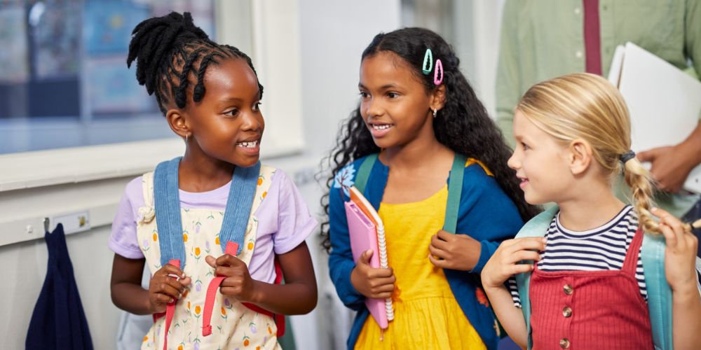 three girls with backpacks walking down the hall