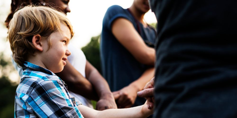 child holding hands with parents in the park