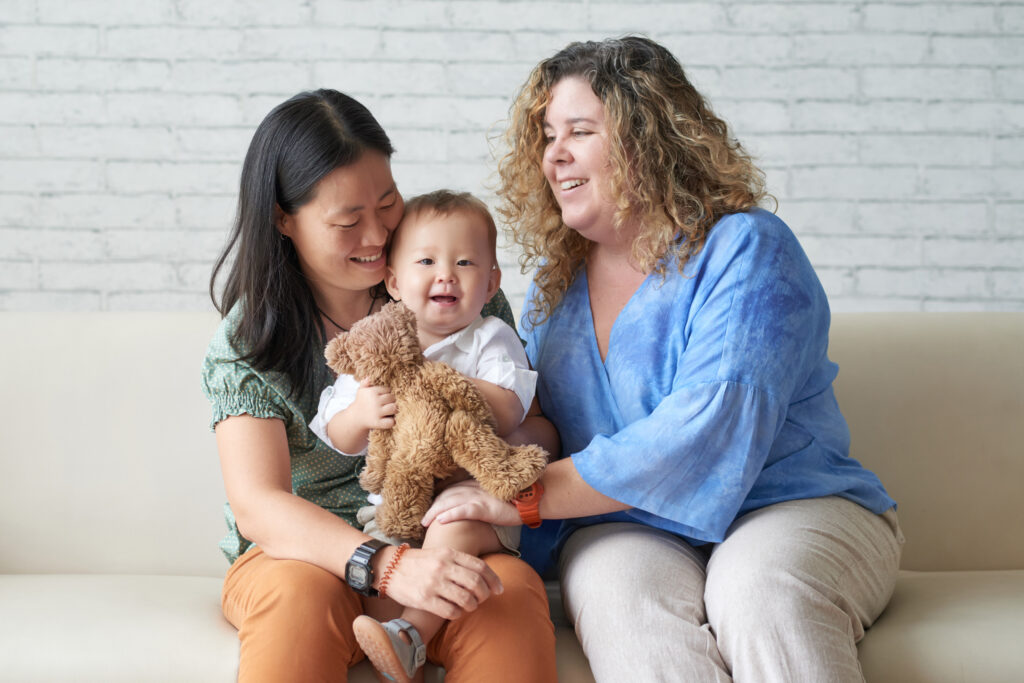 lesbian couple with their child sitting on a couch