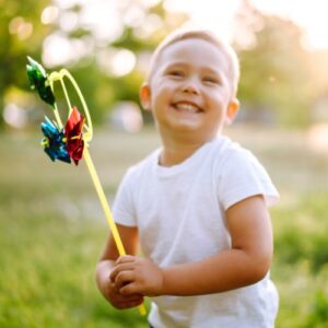 kid smiling while holding a toy outdoors