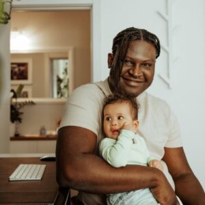 Man sitting at desk holding his infant kinship care relative