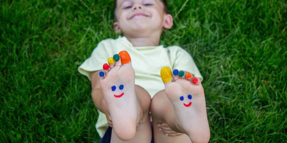 Boy with happy faces painted on his feet because of the Socktober impact