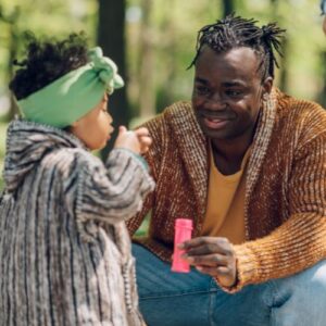 Man with his kinship care daughter blowing bubbles