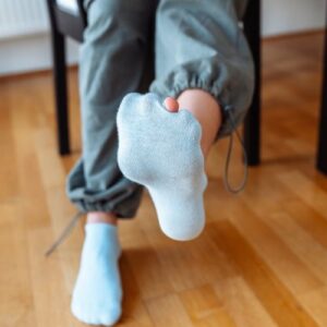 Child wearing a worn out sock with a hole in it, toe is poking through