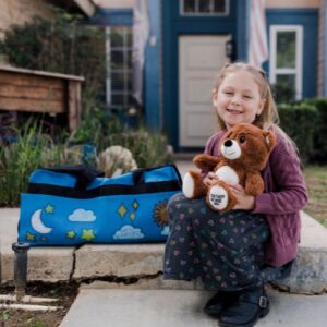 Girl sitting with her Sweet Case holding a teddy bear