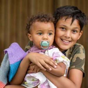 A brother holding his toddler sibling