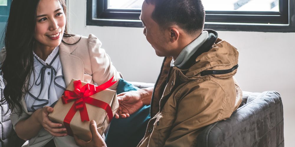 Man handing a woman a gift in a box with a bow