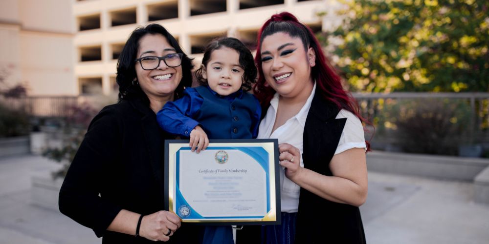 Moms holding their daughter and adoption certificate