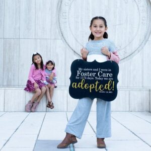 A girl holding up a sign saying she and her sisters were adopted