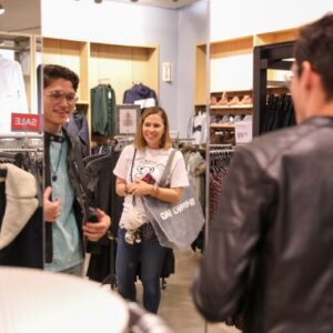 Boy looking happily in the mirror while he wears a new jacket