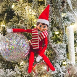 Elf on the shelf next to an ornament