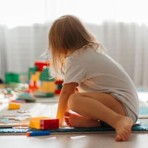 girl playing with toys, back turned to camera