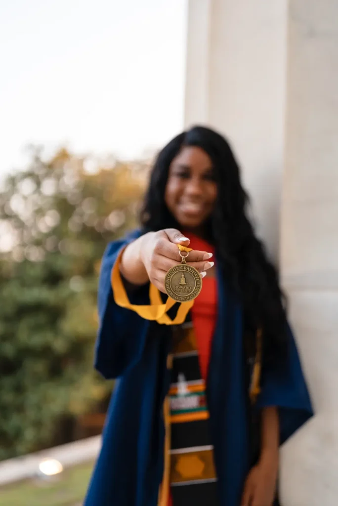 Foster Love Family Fellowship scholar in graduate gown showing off her medal.