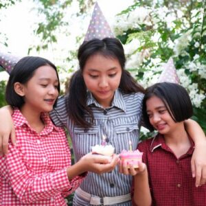 three girls in hats holding cupcakes