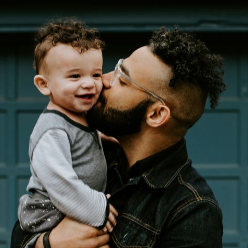 father holding kissing son on cheek