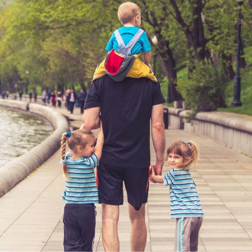 father with three kids hand in hand and on his shoulders
