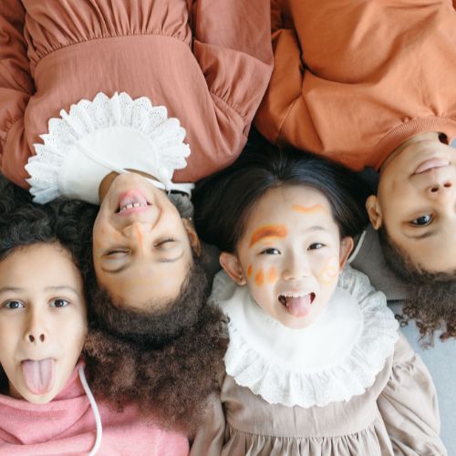 4 children laying on floor looking up at camera