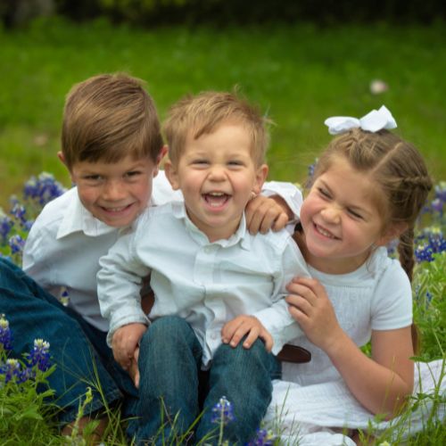 three siblings in the grass
