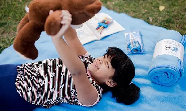 child holding up snuggle kit bear